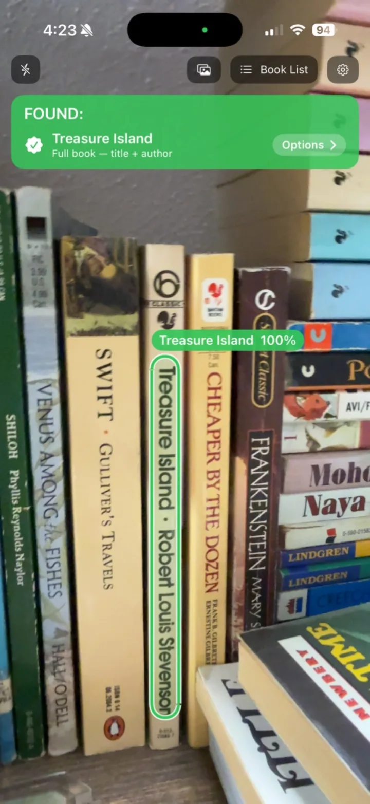 Book Spotter on iPhone: a green FOUND banner for Treasure Island, with the matching spine boxed in green on a crowded shelf